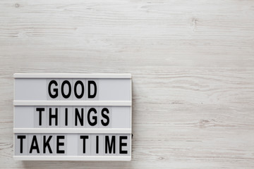 'Good things take time' words on a lightbox on a white wooden surface, top view. Overhead, from above, flat lay. Copy space.