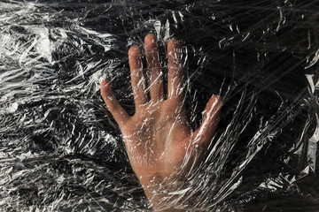 Human hand on background of plastic trash polluting planet. Stop the use of plastic packaging and bags.