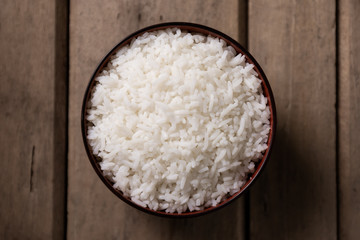 White rice in black bowl on wooden background