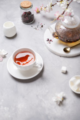 Fragrant tea in a cup and teapot on gray background. Spring tea party. Cafe, reastaurant menu, poster, greeting card. Copy space