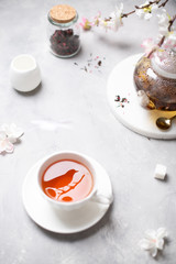 Black tea composition. A cup of fragrant tea with fruits and flowers and a teapot. Spring mood. Poster, greeting card, menu