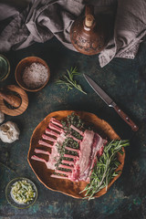 Lamb racks cooking preparation. Raw lamb ribs with fresh rosemary and time on wooden cutting board on dark rustic kitchen table background. Top view. Meat food
