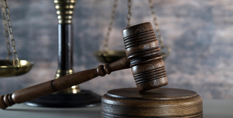 Law and Justice concept. Mallet of the judge, books, scales of justice. Gray stone background, reflections on the floor, place for typography. Courtroom theme.. Wooden rustic background