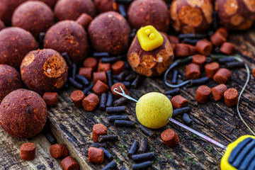 Carp fishing chod rig.The Source Boilies with fishing hook. Fishing rig for carps, boilie rig, near the lake on a piece of wood - obrazy, fototapety, plakaty