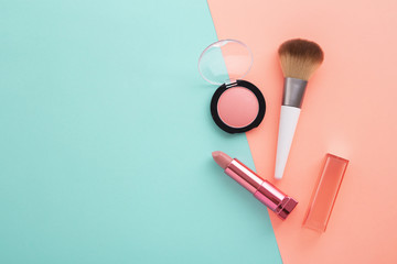 Lipstick, blush and brush on pastel color background