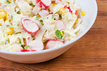 Salad of crab sticks with vegetables in bowl, fragment closeup