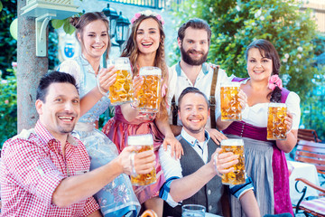 Group of merry people drinking beer looking into the camera
