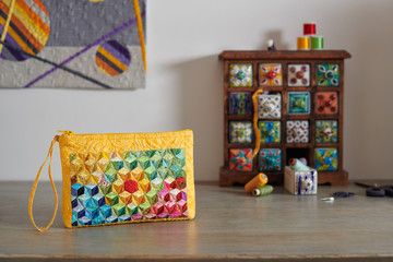 Patchwork wristlet on the background.wooden mini chest with ceramic drawers