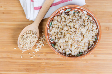 Pearl barley porridge and uncooked pearl barley groats, top view