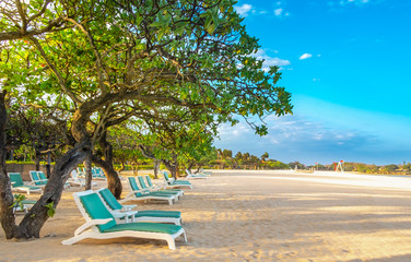 Empty sun loungers on a white sandy beach on a tropical coast on a clear Sunny day