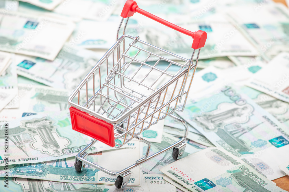 Aufkleber grocery cart with a red handle on the background of 1000 ruble banknotes.