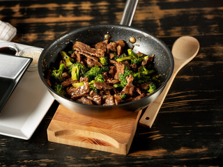 Beef meat and broccoli vegetable cooking in pan close up, selective focus. Traditional food recipe.