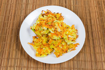 Savory cabbage pancakes on dish on bamboo table mat