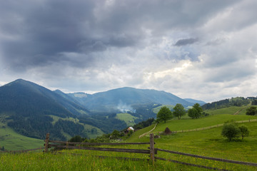 Fototapeta na wymiar Carpathian slopes with fenced hayfields on a foreground