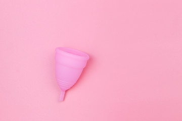 Pink reusable silicone menstrual cup on pink background. Top view, copy space. Concept of feminine hygiene, gynecology and health