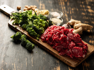 Fresh healthy broccoli vegetables and raw meat cutting on wooden desk. Close up. Cooking recipe concept.