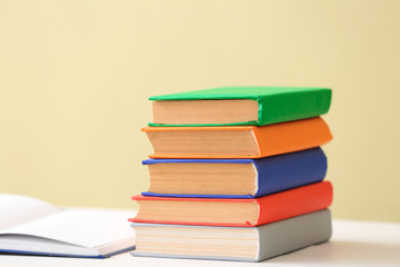 Many books on table against color background