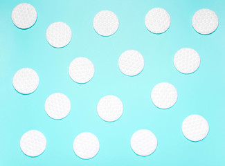 White cotton disks on blue background. Concept of cleanliness, makeup, body care.