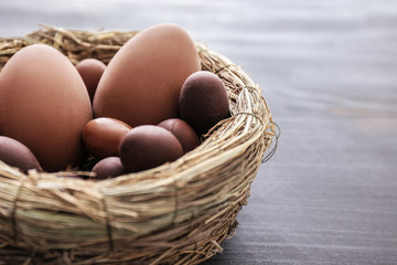 Nest with tasty chocolate Easter eggs on wooden background