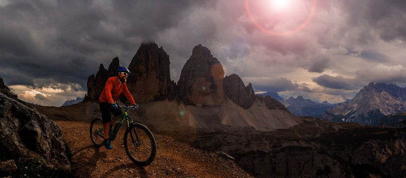 Cycling outdoor adventure. Man cycling on electric bike, rides mountain trail. Man riding on bike in Dolomites mountains landscape. Cycling e-mtb enduro trail track. Outdoor sport activity. © Gorilla