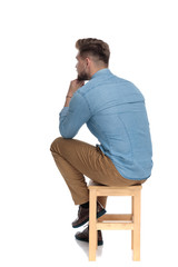 pensive casual man holding hand to chin and thinking