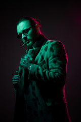 Guy with toothpick in his mouth, beard in glasses on black background