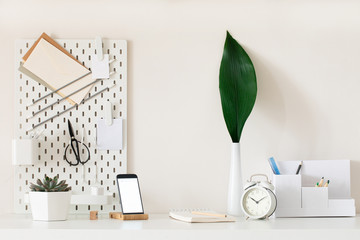 Stylish desk interior with White table background with plant and leaves. Modern home office interior