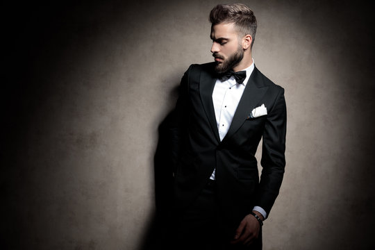 elegant fashion man in tuxedo posing in a fashion light