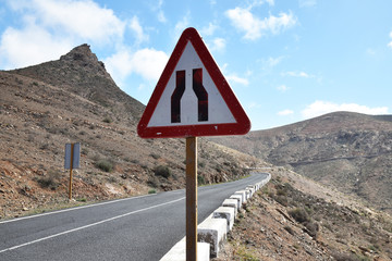 Triangular warning sign for road narrowing on mountain road in Fuerteventura, Spain