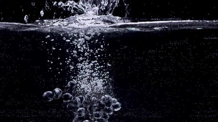 Bunch of grapes falling into water in slow motion. Isolated on black background. Close up view. Shot with cinema camera RED Dragon, UHD, 240fps. - Powered by Adobe