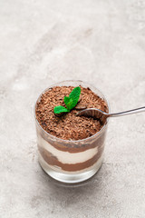 Classic tiramisu dessert in a glass cup on concrete background