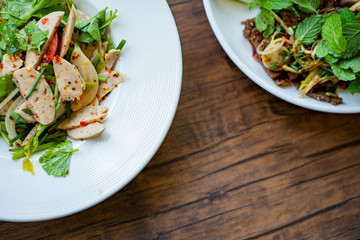 A portion of food on the white dish, wood background.