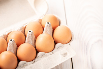 Brown chicken eggs in carton box on white background, space for text