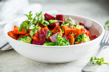 Baked sweet potato, beetroot and broccoli salad in white bowl.