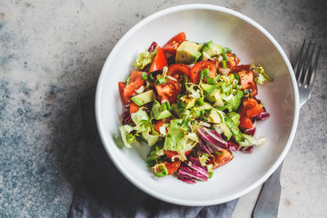 Avocado and tomato salad in white bowl, top view. Vegan food concept.