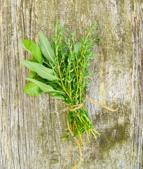 Bunch of fresh green organic herb leaves on old wooden background. Thyme, Sage, Oregano, Basil and Mint closeup. Aromatic culinary herbs. Bundle of freshly picked kitchen herbs.