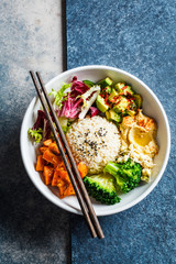 Vegan rice and vegetables salad, top view. Macrobiotic set with rice, hummus, avocado, broccoli and sweet potato.