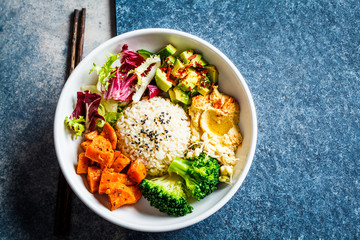 Vegan rice and vegetables salad, top view. Macrobiotic set with rice, hummus, avocado, broccoli and sweet potato.