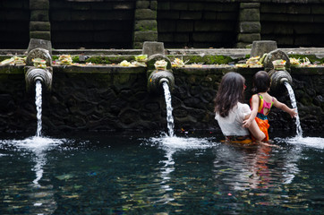 A woman and a girl in the Tirta Empul temple in Bali