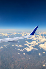 Airplane flying at high altitude over green mountains and sky at sunrise