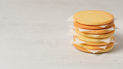 Stack of homemade cookies on a grey background. There are paper slices between the cookies. Close up. Macro photo