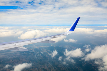 Fototapeta premium Airplane flying at high altitude over green mountains and sky at sunrise
