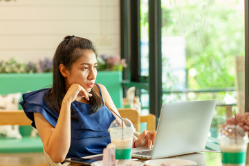 young asian woman sitting in coffee shop and using laptop