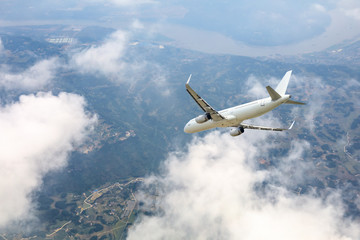 Airplane flying at high altitude over green mountains and sky at sunrise