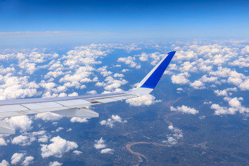 Airplane flying at high altitude over green mountains and sky at sunrise