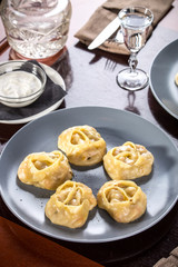 Stuffed dumplings manti from dough and minced meat and vodka shot on wooden table at restaurant