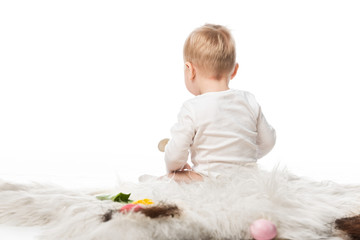 Back view of cute kid sitting on fur isolated on white