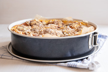 ganzer Bratapfelkuchen in einer Backform auf hellem weißen Holzgrund mit Küchentuch