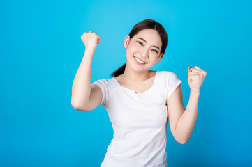 Fototapeta premium Beautiful young asian woman pretending to be happy with big smile happy beaming face in seamless blue isolated background.