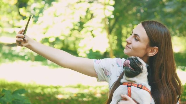 Woman is taking selfie by mobile phone with her pug dog. Close up. Copy space. 4K.